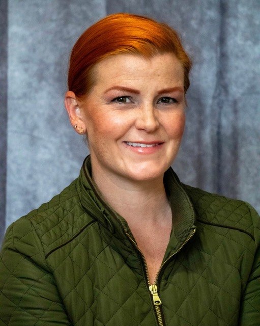 Jackie Nash in a green quilted jacket, photographed against a grey studio backdrop.